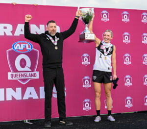 Matthew Lappin, Southport Sharks QAFLW couch, holding up the 2025 QAFLW premiership cup with Southport Sharks seniors captain, Rhiana Schipp.